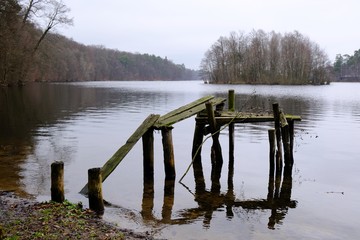 Wooden destroyed jetty at a lake in an autumn day. Lapinskie Lake, Lapino, Kashubia, Poland