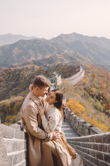 Naklejka premium beautiful young couple showing affection on the Great Wall of China. Newly married couple on their honemoon to Great Wall near Beijing China. Stylish couple exploring one of the wonders of the world