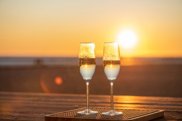 two glasses of champagne on the table at sunset