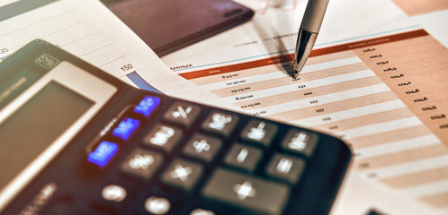Calculator to analyze the graph and chart. Pen indicating numbers.
