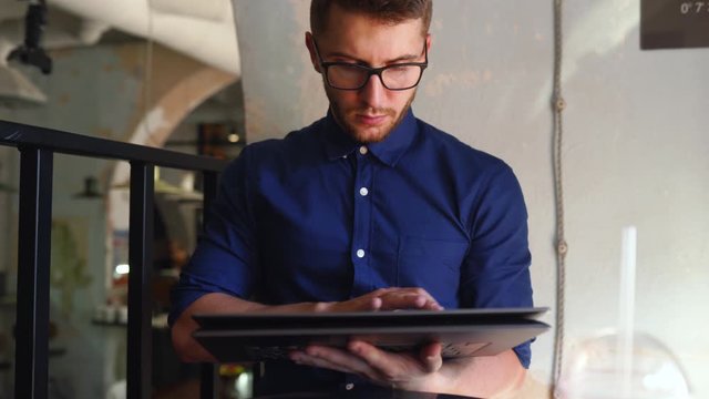 Freelancer man transforms convertible laptop to tablet mode and works with touchscreen. Digital artist use 2 in 1 computer with touch screen digitizer for making his business project in cafe.