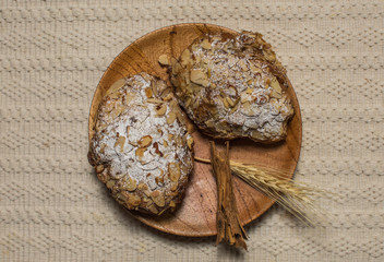 Traditional French croissant with almonds on the wood plate on white color fabric texture background