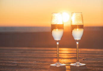 two glasses of champagne on the table at sunset