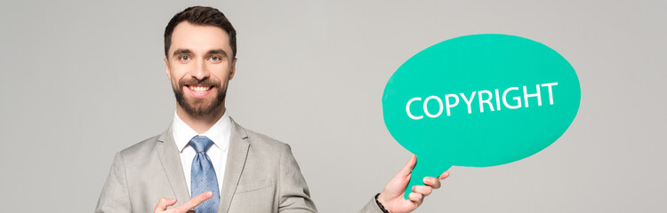 panoramic shot of smiling businessman pointing with finger at thought bubble with copyright...