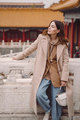 stylish girl visiting the forbidden city in Beijing China during autumn