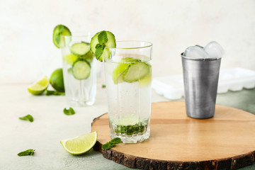 Glass of cold cucumber water on light background