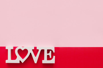 The word love consists of wooden letters located on a pink and red background. Greeting card Valentine's Day and Women's Day