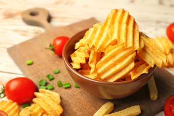 Bowl with tasty potato chips on table