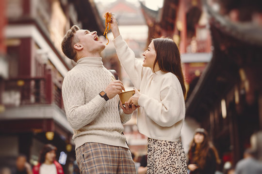 Newlywed Couple Eating Noodles With Chopsticks In Shanghai Outside A Food Market Near Yuyuan. Couple Eating Authentic Local Food. Husband And Wife Eating Chinese Food Outisde Of A Food Hall