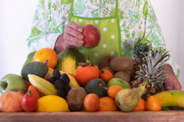 One people holding a large wooden basket filled with freshly picked fresh fruit. In his hand a red apple