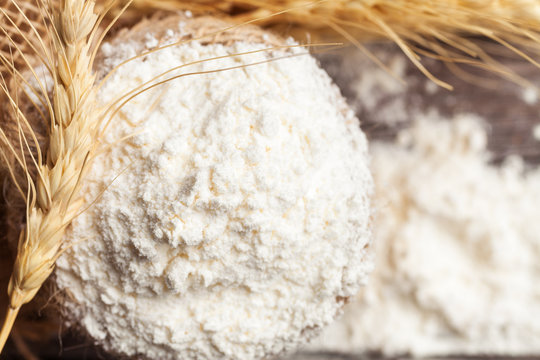Flour in burlap bag with wheat ears on wooden background. Food background 