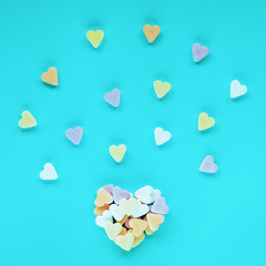 Heart made of colorful sugar candies on a blue background. Valentine's Day concept. Top view, flat lay.