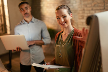 Happy businesswoman giving presentation to her coworkers in the office.