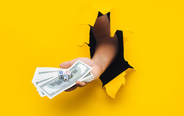 Men's hands hold a pack of hundred-dollar bills and dice, as a symbol of gambling, casino and good...