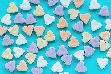 Colorful sugar candies in a shape of hearts on blue background. Creative holiday concept of love. Valentine's day.
