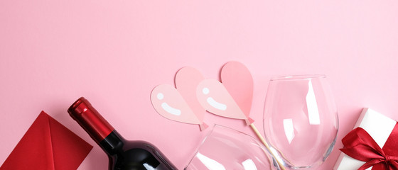 Valentine's Day banner template. Top view pink background with valentine gift, bottle of wine champagne, glass, hearts. Minimal flat lay style composition. Romantic dinner couple concept