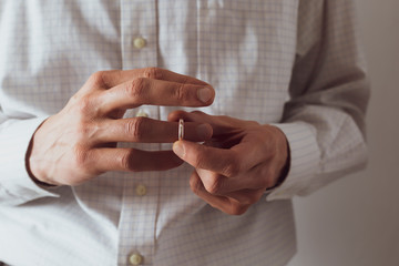 Treason. A man takes off his wedding ring about to cheat on his wife.