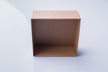 Empty small cardboard box. Standing on a rib, blue background.