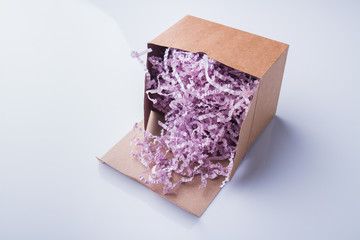 Purple pink shredded paper gifting stuffing cardboard box. Isolated on white.