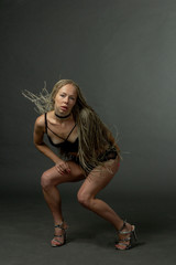 A girl with African hairdo pigtails dread with a technique of zizi, moves dancing on a light background in dark underwear.