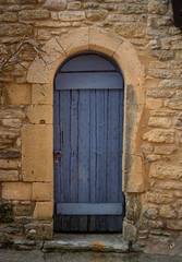 Fototapeta na wymiar Old blue door in yellow stone wall with padlock.