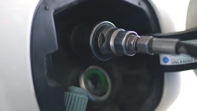 Gas man putting natulal gas in the car's gas tank of a white ecologic methane fueled car at a cng pump. Shot in 6k.
