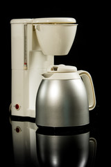 Plastic white filter coffee maker or machine with stainless steel mug isolated on black on...