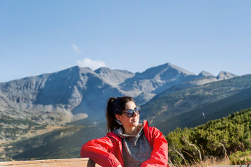 Fototapeta na wymiar Woman Sitting on a Bench in the High Mountain 