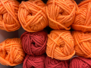 a shelf with colored orange and red skeins of thread for knitting. Crochet and knitting. Hobbies for women