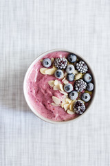 Healthy breakfast berry smoothie bowl topped with banana, granola, Blueberries and chia seeds with copy space