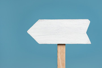 Wooden signpost on blue background. Arrow pointer. Front view, closeup