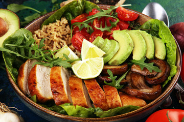 Healthy salad bowl with quinoa, tomatoes, chicken, avocado, lime and mixed greens and mushrooms