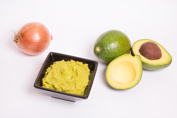 Guacamole con aguacates y cebolla sobre fondo blanco.