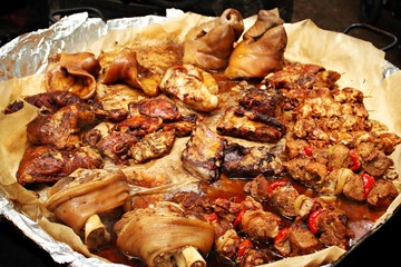 Pieces of pork meat cooked on a fire and spread out on a large tray