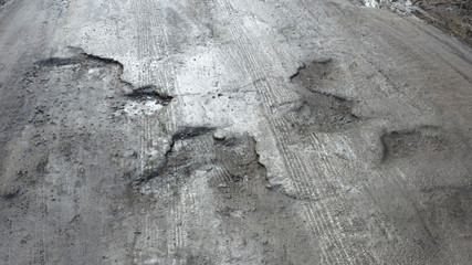 Large pits are filled with water on an asphalt road