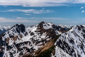 Obraz premium Amazing mountain peaks covered with snow. Beautiful clouds are on a background. Flight seeing tour by helicopter in Alaska. 