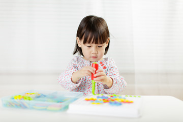 toddler girl playing creative toy blocks at home against white background