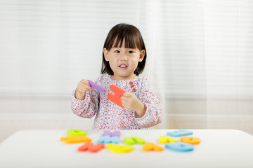 toddler girl learning alphabet letter at home against white background