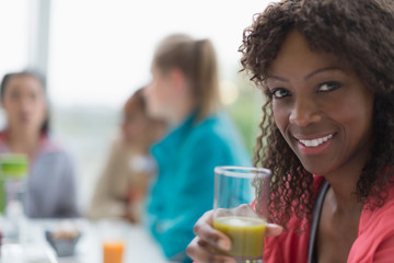 Portrait smiling woman drinking healthy green smoothie at cafe friends