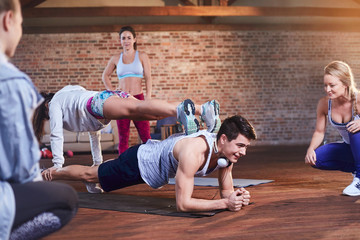 Young man and woman practicing stacked plank pose in gym studio
