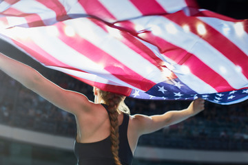 Female athlete running victory lap with American flag