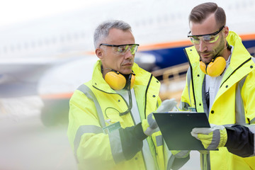 Air traffic controllers with clipboard talking on airport tarmac