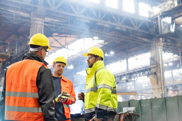Steel workers talking in factory