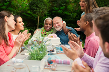 Affectionate multi-ethnic senior couple hugging celebrating anniversary at patio table