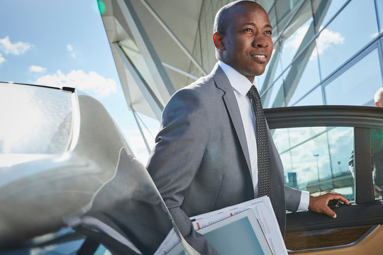 Businessman Arriving At Airport Getting Out Of Town Car