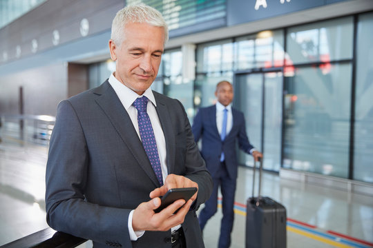 Businessman texting with cell phone in airport concourse