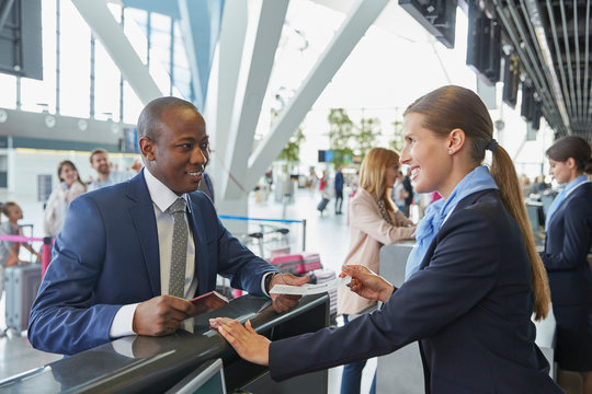 Customer service representative helping businessman at airport check-in counter