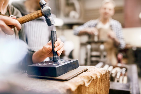 Jeweler using hammer and equipment in workshop