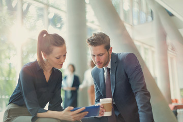 Business people drinking coffee using digital tablet in office lobby