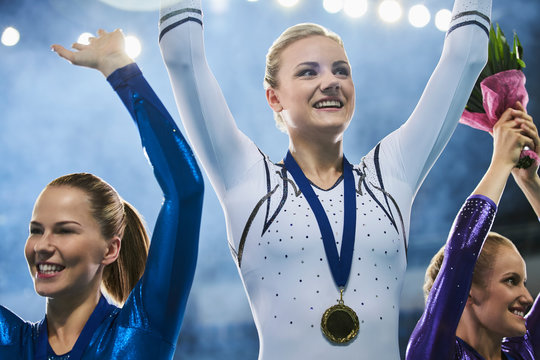 Female gymnasts celebrating victory waving on winners podium